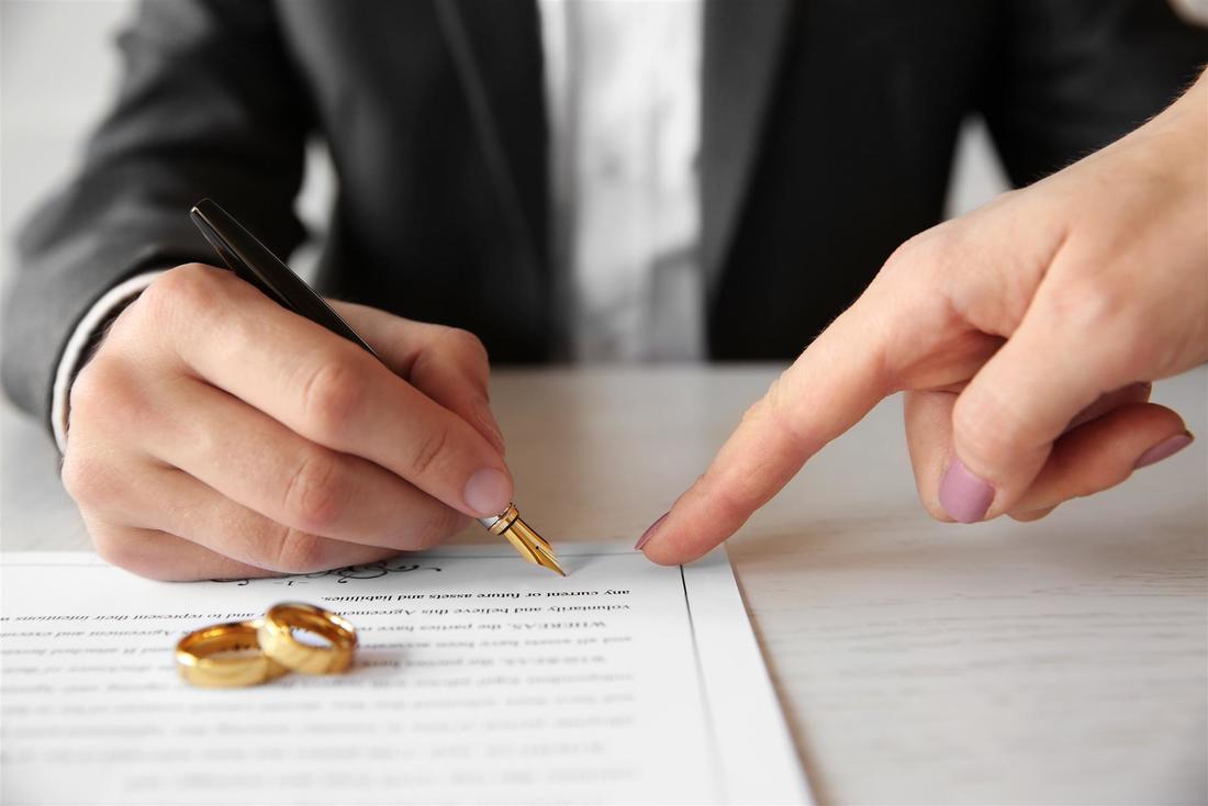 man signing marriage certificate and gold wedding rings